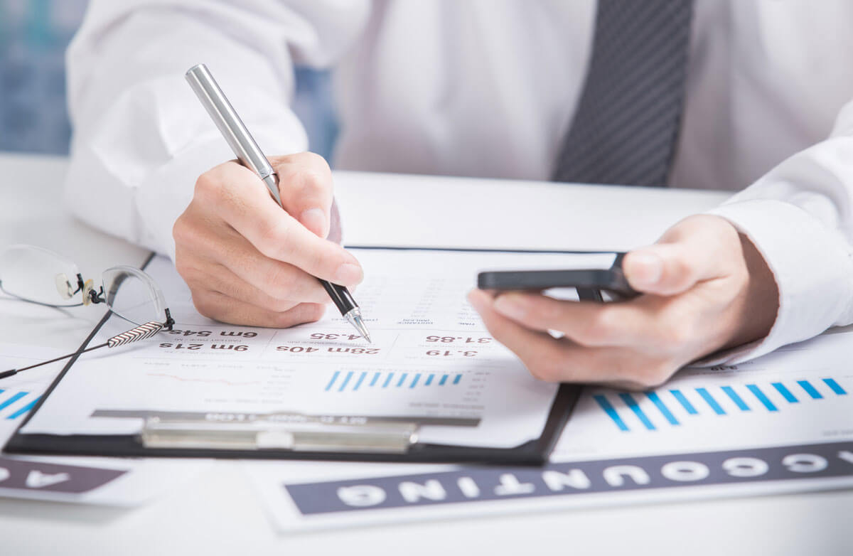 Person analysing data charts with pen and smartphone.