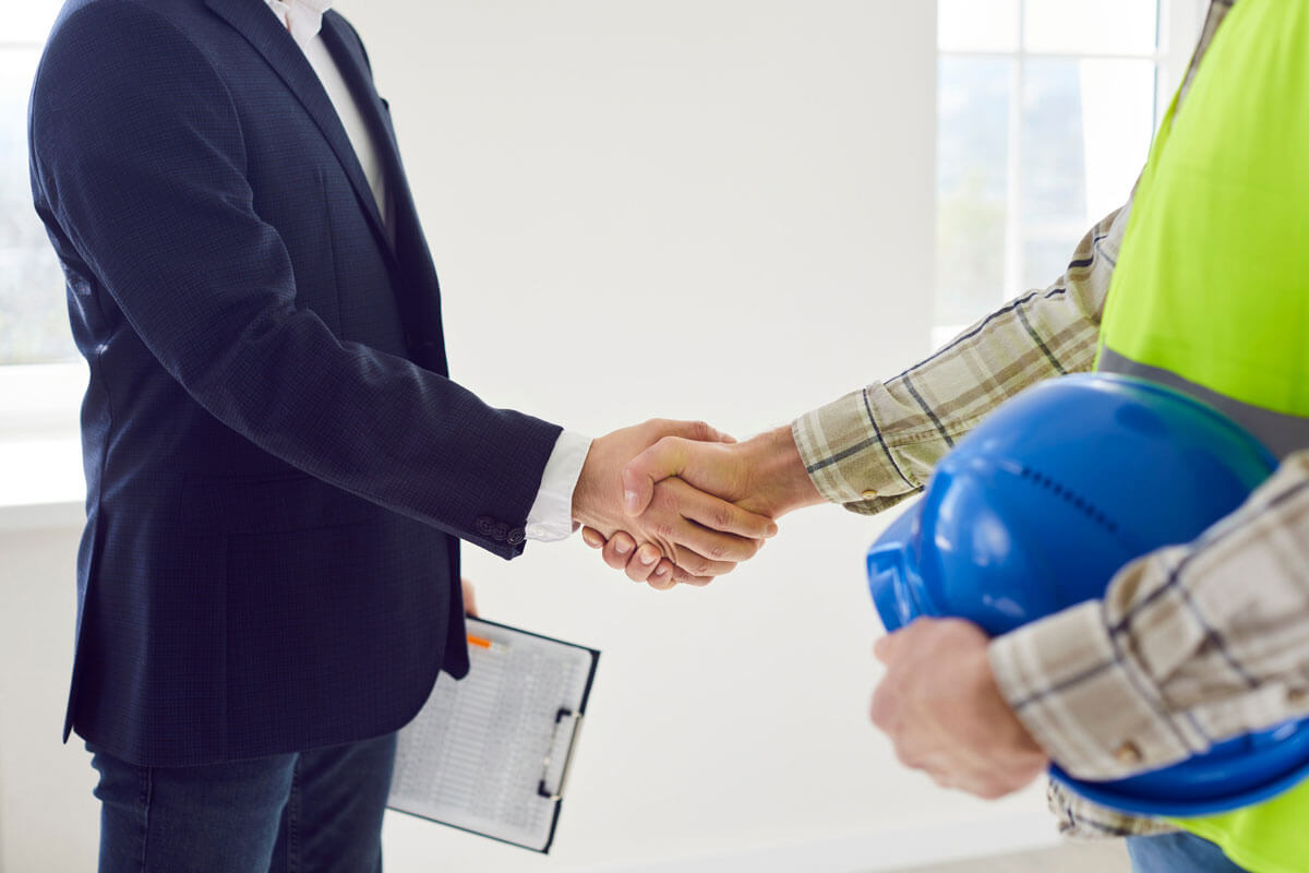 Business and construction professionals shaking hands indoors.