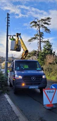 Man in lift repairs power line from van.