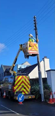 Worker repairing electrical lines in a cherry picker.