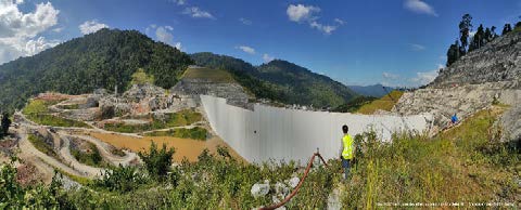 Large dam in mountainous landscape under clear sky.